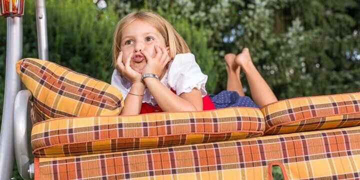 Bambina sdraiata sui cuscini del dondolo