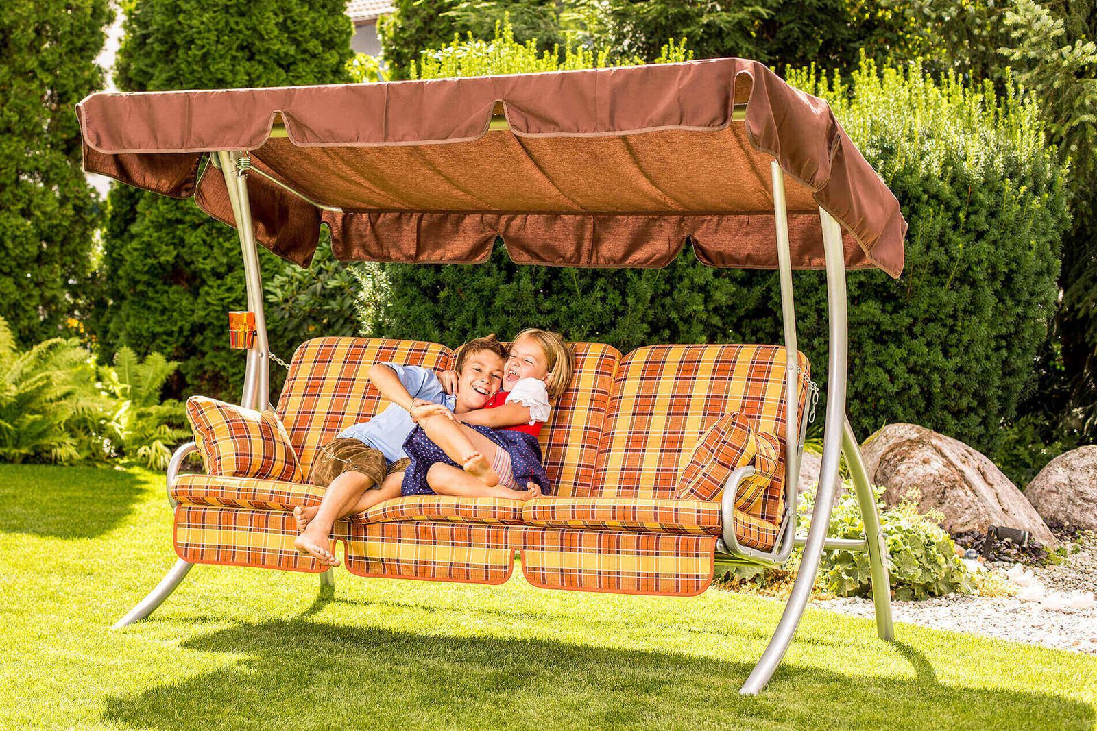 Papà e figli abbracciati su un dondolo a quadri in giardino