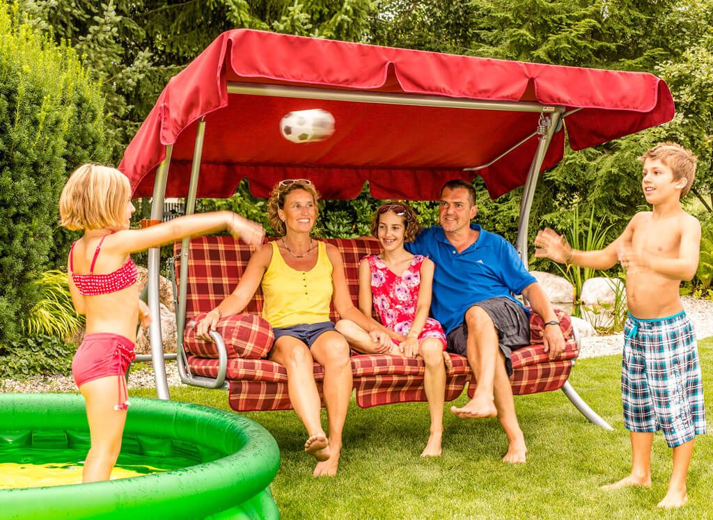 Famiglia con bambini sul dondolo in giardino accanto alla piscina