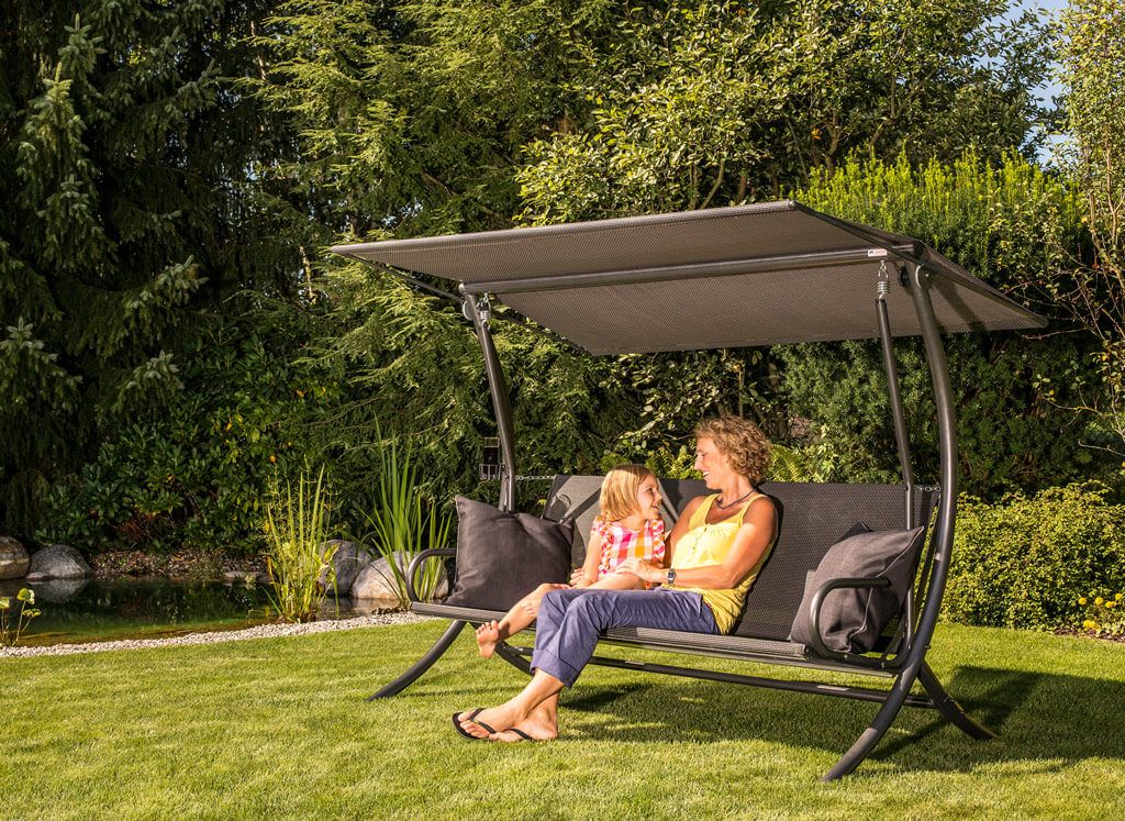 Mamma e figlia su un dondolo moderno grigio in giardino